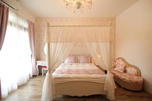 花莲市齐亚风情的一间卧室配有一张天蓬床和吊灯。