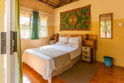 卡萨内African Sunsets (Bophirimo Self-Catering Guest House)的卧室配有一张床,墙上挂有绘画作品