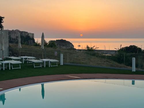 特罗佩阿Residence New Paradise的游泳池边的日落美景,设有桌椅