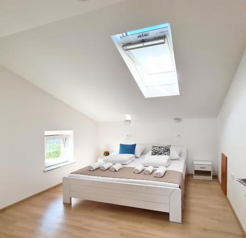 塞扎纳Hisa idej的白色卧室配有一张带天窗的床