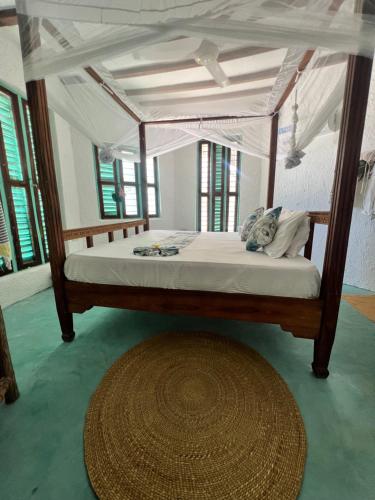 帕杰Duara Beach House的一间卧室配有一张天蓬床和地毯。
