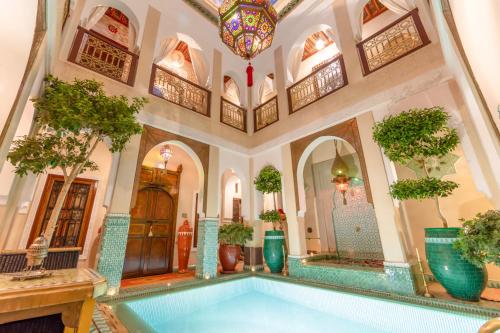 马拉喀什利亚德童话庭院旅馆的一座种植了盆栽植物的建筑中的室内游泳池