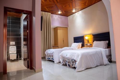 杜阿拉HOTEL MICKEL的酒店客房设有两张床和一个步入式淋浴间。