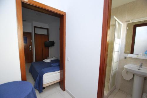 滨海比拉萨尔Hotel Tres Leones的一间卧室配有一张床,浴室设有水槽