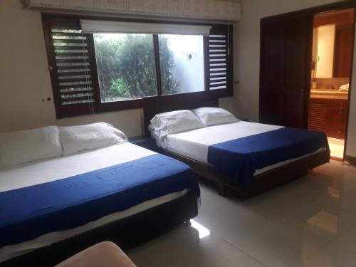 卡利Casa Jardin del Lago的一间卧室设有两张床和窗户。