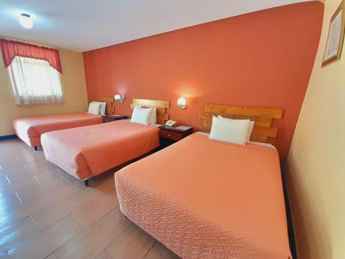 克萨尔特南戈Hotel y Restaurante Villa Esmeralda的橙色墙壁的酒店客房内的两张床
