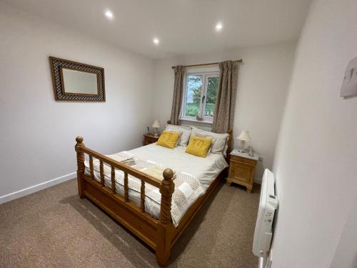 法弗舍姆Little Owl Cottage的一间卧室配有一张带黄色枕头的床和一扇窗户