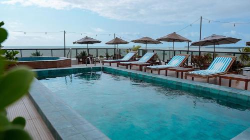 若昂佩索阿阿特克皮亚酒店的一个带躺椅和遮阳伞的游泳池