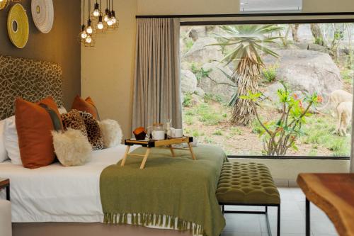 内尔斯普雷特Pumbaa Wildlife Park & Accommodation的一间卧室配有一张带桌子和窗户的床