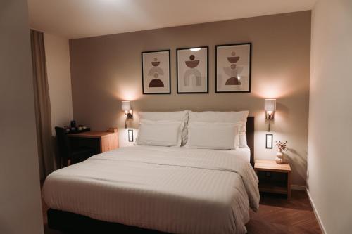 德莱蒙Hôtel du Midi的卧室配有一张带两张桌子的大型白色床