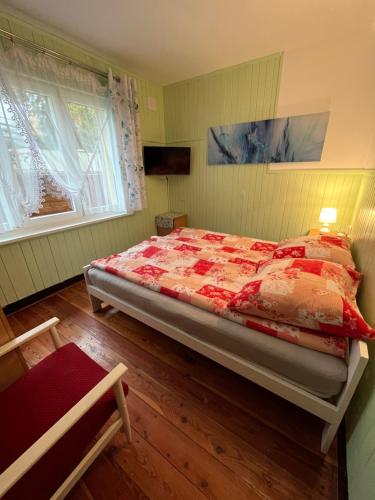 罗威A&R Brzozowa 5的一间卧室配有一张红色棉被的床和两个窗户