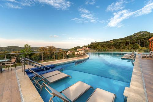格拉玛多Laghetto Resort Golden Oficial的阳台的游泳池及其躺椅