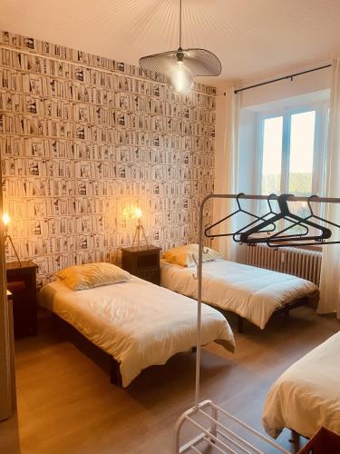 拉佩蒂特皮耶尔LA MARIEFACTURE - Comme un Livre Ouvert的一间卧室设有两张床和一张带照片的墙壁