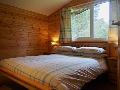 卡布里奇Reuben's Highland Retreat - Speyside的一间卧室设有一张床和一个窗口