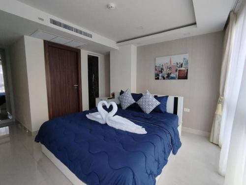 芭堤雅市中心Grand Avenue Pattaya的一间卧室配有一张蓝色的床,上面有毛巾