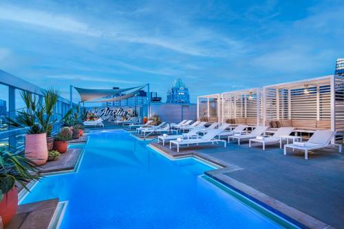 奥斯汀奥斯汀市中心欧尼酒店的一座带白色椅子的建筑屋顶上的游泳池