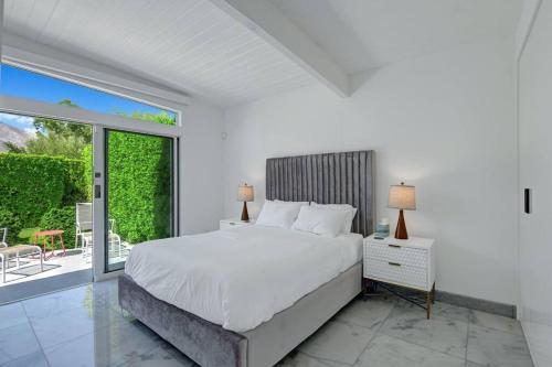 棕榈泉Palm Springs Luxury Home With a POOL, Next to Downtown & Airport的白色卧室设有一张大床和一个阳台