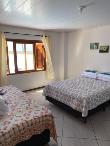 里奥格兰德Casa Beira Mar com Piscina的一间卧室设有两张床和窗户。