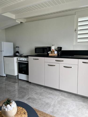 KoolbaaiJm.HouseSxm的厨房配有白色橱柜和黑色台面