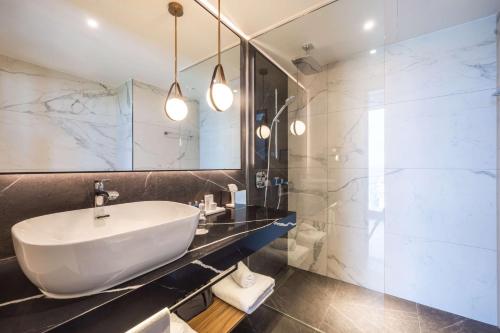 斯图加特Radisson Blu Hotel at Porsche Design Tower Stuttgart的浴室配有白色水槽和淋浴。