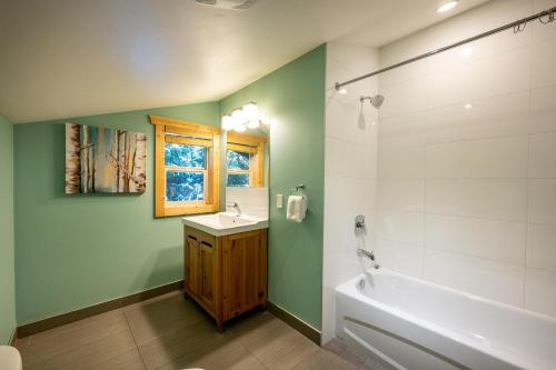 惠斯勒Chalet Whistler - Family Chalet, Hot Tub, BBQ, Cinema, Putting Green - Whistler Platinum的浴室配有白色浴缸和水槽