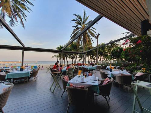 华欣Anantasila Beach Resort Hua Hin的海滩上的餐厅,配有桌椅
