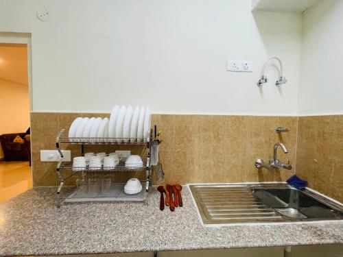 勒克瑙ALanKrita Homes的厨房柜台设有水槽和架子上的白杯