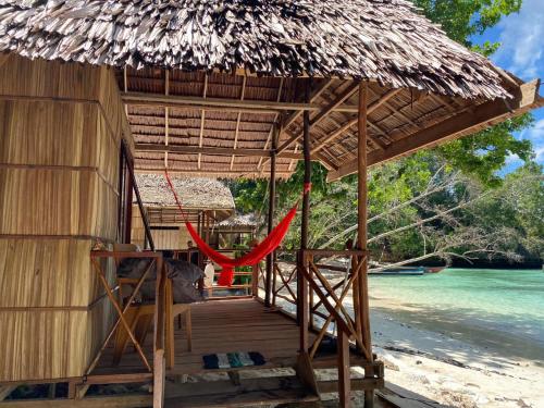 Yennanas BesirI&D Home Stay Raja Ampat的海滩上带吊床的小屋
