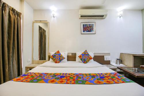 博帕尔FabHotel Smriti Star的一间卧室配有一张带彩色毯子的床