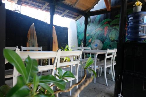 龙目岛库塔Surf Camp 79的一间设有桌椅的用餐室和墙上的冲浪板