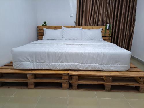 伊巴丹Igbalode Luxury Apartment的一张位于木制平台上的床铺,配有白色床垫