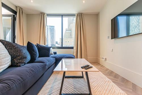 利物浦Luxurious 1 Bed - CITY VIEW的客厅配有蓝色的沙发和玻璃桌