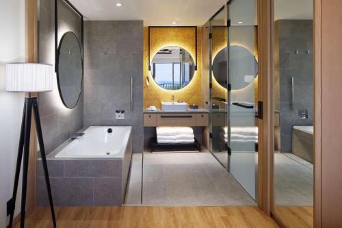 本部Hilton Club The Beach Resort Sesoko的带浴缸、水槽和镜子的浴室