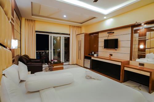 曼达莫尼Prasant Beach Resort的酒店客房设有白色的床和电视。