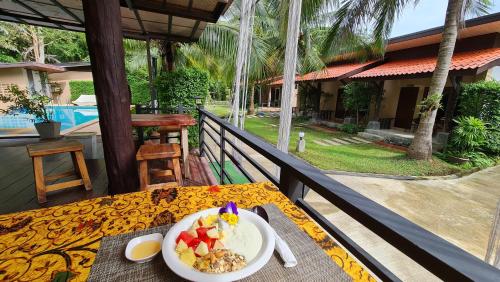 高兰Baan Suan Rim Klong Resort的阳台上的桌子上放着一碗食物