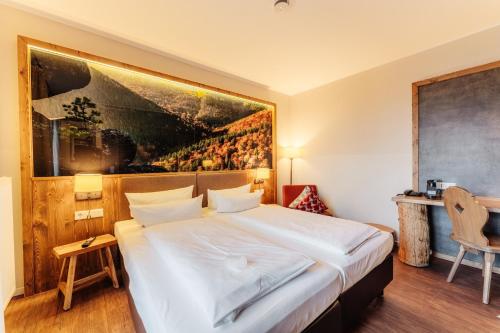 托夫豪斯陶夫豪斯哈尔茨度假酒店的卧室配有一张大床,墙上挂有绘画作品