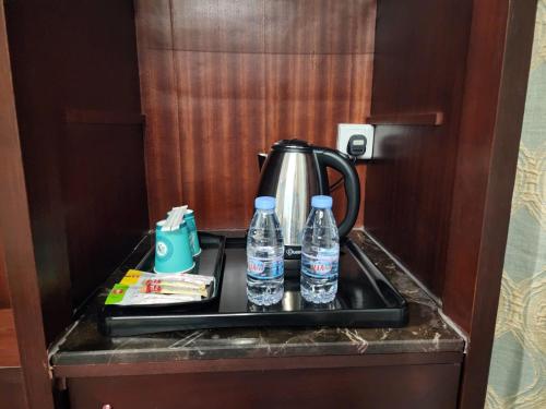 吉达EWG Al Hamra Hotel的茶壶和托盘上的两瓶水