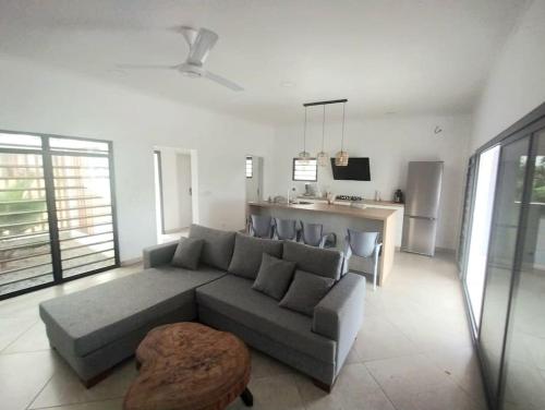 利伯维尔Villa en résidence à Malibé Libreville的一间带灰色沙发的客厅和一间厨房