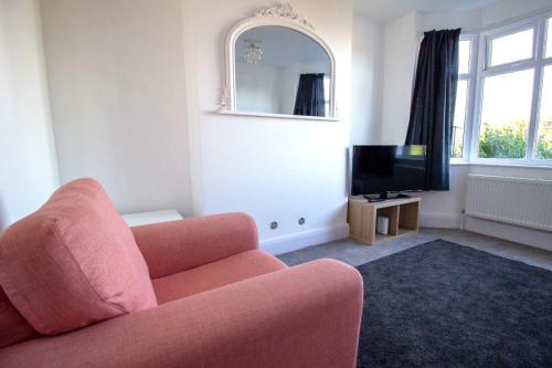 格兰瑟姆Fully renovated spacious home, Sleeps 5,的客厅配有粉红色的沙发和电视