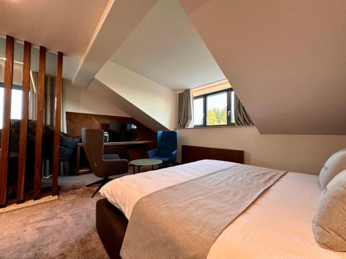 莱斯拉塞斯Hôtel Restaurant & Spa Les Planets的一间卧室配有一张床、一张桌子和一把椅子