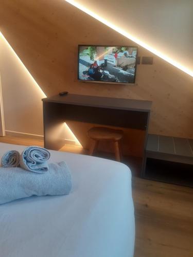 圣维托-迪卡多雷Appartamento Vale e Schena Cortina D'Ampezzo的一间卧室配有一张床和一张书桌及电视