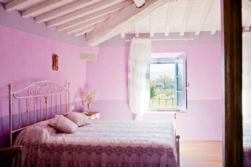 斯卡尔佩里亚Tenuta Le Tre Virtù的粉红色的卧室设有床和窗户