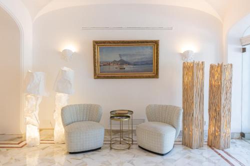 卡普里马美拉酒店的一间设有两把椅子的房间和墙上的一幅画
