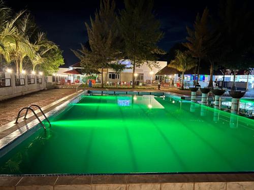 WakisoKakiri Gardens and Hotel的游泳池在晚上提供绿色照明