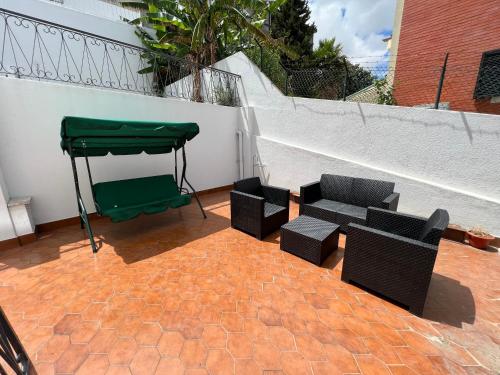 奥埃拉斯Oeiras Beach guest house的天井配有两把椅子和绿色天篷