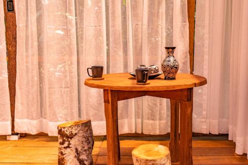 伊基托斯Family hotel PURMA CASPI on the jungle lake的一张木桌,上面有两个杯子和花瓶