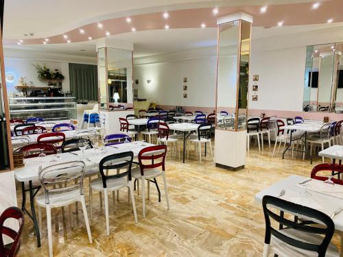 里米尼hotel iris的一间设有白色桌椅的用餐室