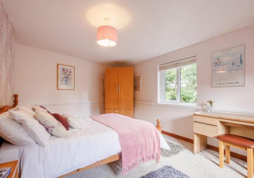 SwimbridgeGranary Cottage的一间卧室配有一张床、一张书桌和一个窗户。