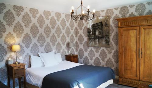 Buzancy索蒙酒店的一间卧室配有一张床和一个吊灯