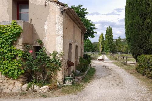 拉聂Chambre d'Hotes Lamanon, avec ou sans petit déjeuner - Domaine Les Peupliers -的一条空的路,旁边是藤蔓的建筑